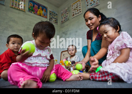 Kleinkinder sitzen mit Kugeln mit ihrem Lehrer zu spielen. Kinder Garten Klasse einer Schule in Attarkhen, Kathmandu, Nepal zu senken. Stockfoto