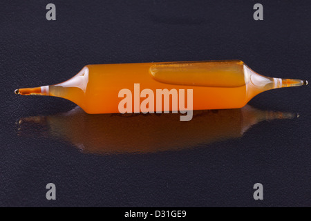 Einem gelben Fläschchen über reflektierende Oberfläche schwarz Stockfoto