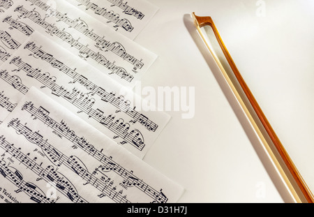 Details zu einem Geigenbogen auf der einen Seite und Noten gedruckt auf Papier, auf der anderen Seite. Stockfoto