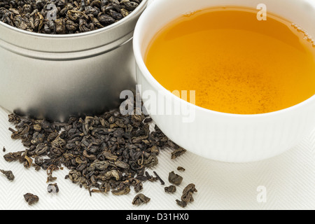 Schießpulver Grüntee - Blätter eine weiße Tasse trinken und lose auf Leinwand Stockfoto