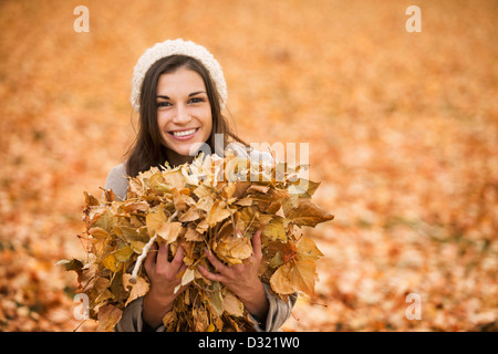 Kaukasische Frau spielt im Herbstlaub Stockfoto