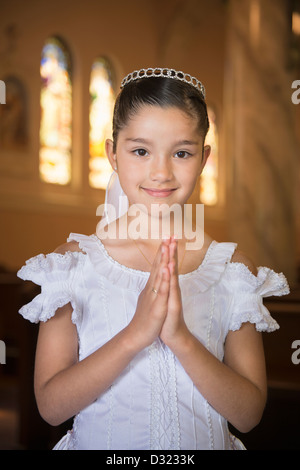 Hispanischen Mädchen mit den Händen umklammert in Kirche Stockfoto