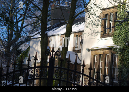 Eine Land Haus Herrenhaus Villa im Winter mit Schnee auf dem Dach durchzuckte Haupttore, Landhaus mit strahlend blauem Himmel und Efeu Stockfoto