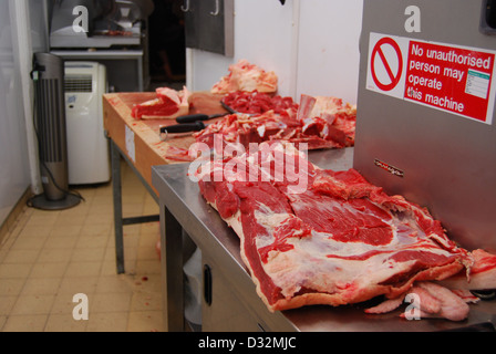 Platten von rotem und weißem Fleisch und Knochen mit Fett auf einem unordentlichen Metzger Tisch bereit, geschnitten und sortiert werden. Stockfoto