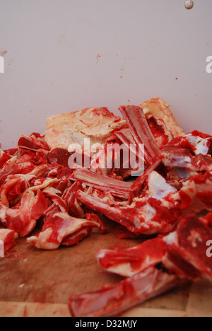 Platten von rotem und weißem Fleisch und Knochen mit Fett auf einem unordentlichen Metzger Tisch bereit, geschnitten und sortiert werden. Stockfoto