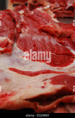 Platten von rotem und weißem Fleisch und Knochen mit Fett auf einem unordentlichen Metzger Tisch bereit, geschnitten und sortiert werden. Stockfoto