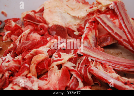 Platten von rotem und weißem Fleisch und Knochen mit Fett auf einem unordentlichen Metzger Tisch bereit, geschnitten und sortiert werden. Stockfoto