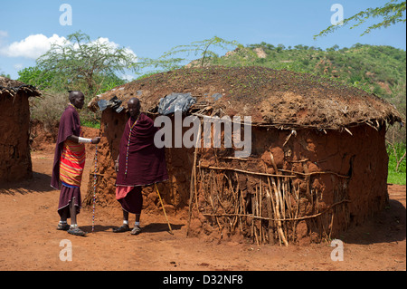 Maasai-Männer und urige Hütten in der Manyatta, Kenia Stockfoto
