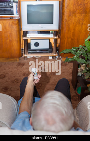 Ältere Menschen vor dem Fernseher zu Hause. Fernbedienung im Mittelpunkt. Stockfoto