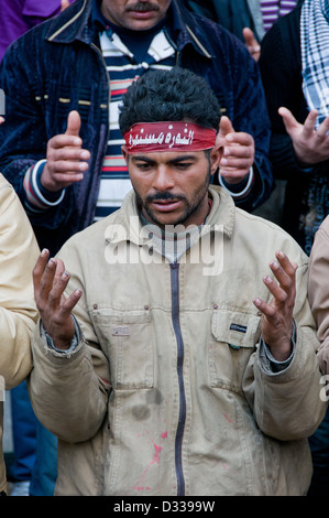 Demonstrator mit Stirnband, das liest: der Aufstand geht weiter betet während einer Protestaktion in Kairo, 31. Januar 2012 Stockfoto