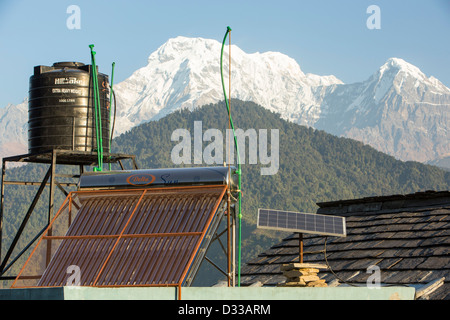 Thermische Sonnenkollektoren für die Warmwasserbereitung mit solar Photo voltaic Paneelen auf den Dächern von einem Teehaus in den Ausläufern des Himalaya, Nepal. Stockfoto