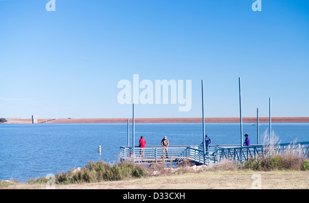 Vier Leute Fischen aus dem Dock im Arcadia Lake in Oklahoma, USA. Im Hintergrund ist die Staumauer. Herbst. Stockfoto