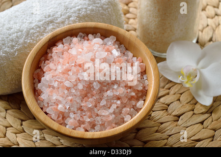 Rosa Salz aus dem Himalaya. Nahaufnahme von rosa SPA Salz in Holzschale mit Orchidee Blume und Handtuch. Stockfoto