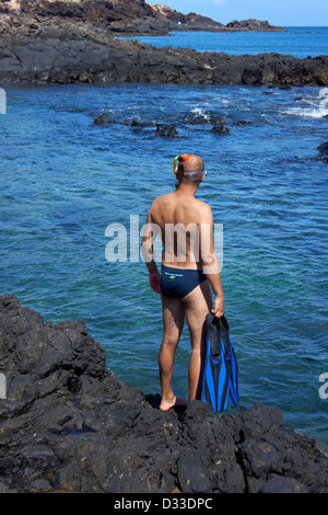 Junger Mann mit Schnorchelausrüstung an der Felsenküste. Kanarische Inseln, Lanzarote. Stockfoto