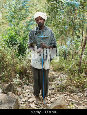 Ein älterer lokalen Pilger Mann trägt ein blaues Kreuz und stand vor einem Wald Stockfoto