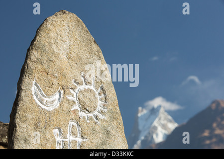 Machapuchare oder dem Heiligen, Fish Tail Peak im Annapurna Himalaya mit einem geschnitzten Symbol Stein im Vordergrund, Nepal. Stockfoto