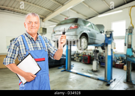 Kfz-Mechaniker hält einen Autoschlüssel in einer Autowerkstatt während eines Kfz-Wartung-service Stockfoto