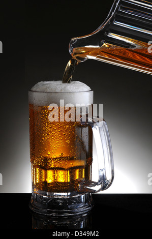 Nahaufnahme von einem Bierkrug aus einem Krug gießt kaltes Bier in das Glas gefüllt wird. Stockfoto