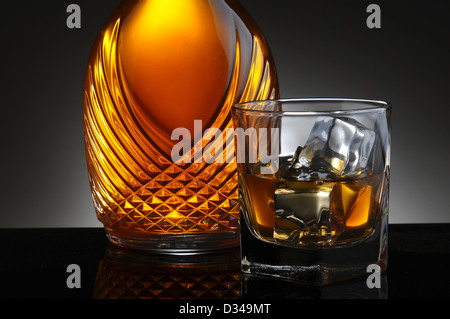 Nahaufnahme einer eleganten Dekanter und ein Glas Scotch auf den Felsen. Querformat auf eine leichte bis dunkelgrauen Hintergrund. Stockfoto