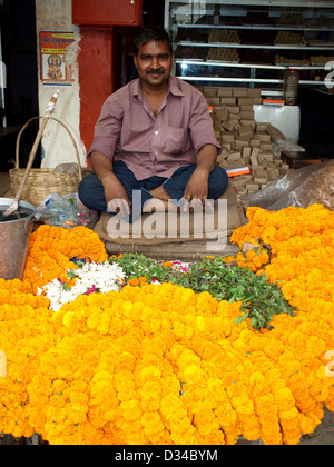 Mann verkauft Puja mit Blumengirlanden außerhalb Tempel in Varanasi, Indien. Stockfoto