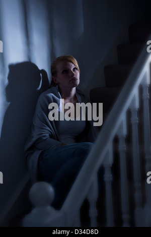 Eine junge Frau, Anfang der zwanziger Jahre oder späten Teenager sitzen allein auf den Stufen, blickte nachdenklich. Stockfoto