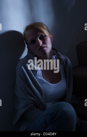 Eine junge Frau, Anfang der zwanziger Jahre oder späten Teenager sitzen allein auf den Stufen, nachdenklichen Blick. Stockfoto