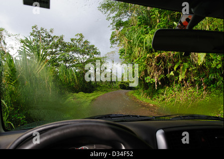 Blick durch die feuchten Windschutzscheibe eines Autos auf einer unbefestigten Straße in der "Volcan Arenal National Park". Costa Rica. Stockfoto