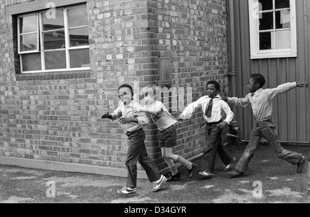 Grundschule Spielplatz. Jungs spielen zusammen. South London. 70er Jahre multirassische multiethnische schwarz-weiße Kinder, die Spaß am gemeinsamen Spielen in der Schule haben 70er Jahre 1975 UK HOMER SYKES Stockfoto