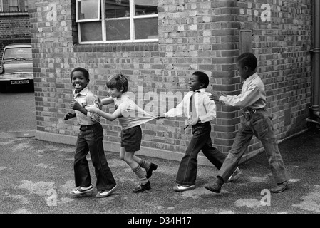 Spielplatz der Grundschule. Jungs spielen zusammen. South London. 1970er Jahre multiethnische multiethnische Kinder in Schwarz und weiß, die Spaß an der Schule haben 1975 UK HOMER SYKES Stockfoto