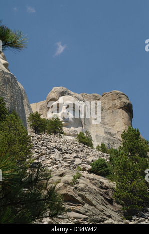 Blauer Himmel Porträt Skulptur Gesicht Abraham Lincoln, Granitfelsen über grünen Bäumen Geröllhalde, Mount Rushmore, S.Dakota, USA Stockfoto