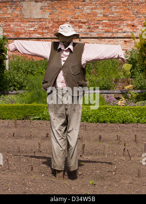 Gut gekleidete Vogelscheuche in ummauerten Garten. Stockfoto