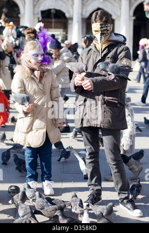 Mutter und Kind in der Fütterung der Tauben in Venedig-Masken Stockfoto