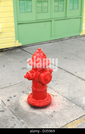 Red Fire Hydrant in der Nähe von gelben und grünen Gebäude Stockfoto