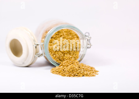 Goldenen Leinsamen in ein Glas jar vor einem weißen Hintergrund. Stockfoto