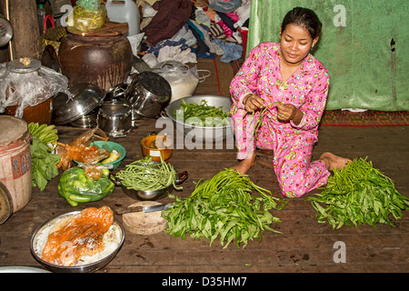 Junge Frau bereitet Prunkwinde Stiele und Spinat zum Abendessen auf der Insel Koh Trong über Mekong River von Kratie, Kambodscha Stockfoto