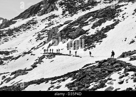 Wanderer zu Fuß auf alpinen Schnee bedeckt Trail in Valnontey, Nationalpark Gran Paradiso, Graian Alpen - Italien (Schwarzweiß) Stockfoto