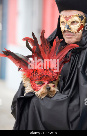 Mann in eine venezianische Maske tragen einen Yorkshire-Terrier Hund in eine Maske für den Karneval in Venedig Stockfoto