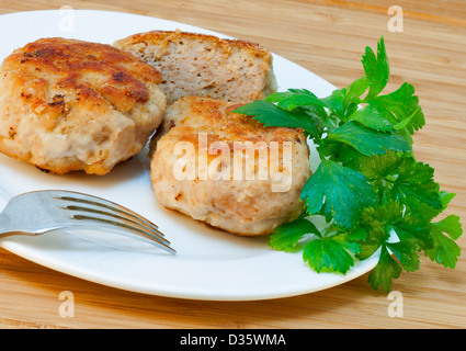 hausgemachte Schnitzel und frischer Petersilie auf einem weißen Teller mit einer Gabel Stockfoto