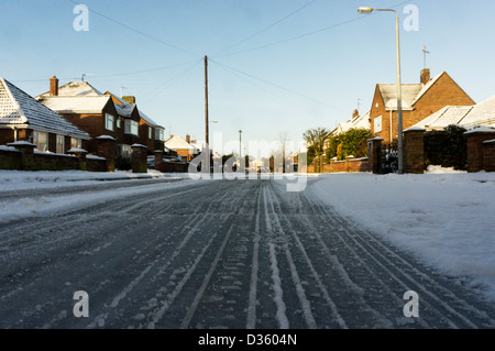 Spurrinnen im Schnee auf einer eisglatten Straße wohnen. Stockfoto