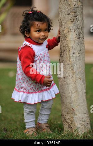 Indischen Baby Mädchen stehen Nest auf einem Baumstamm in einem Garten Stockfoto