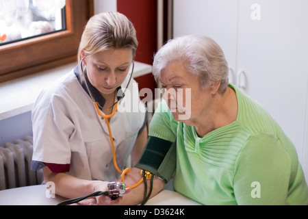 Krankenschwester macht Hausbesuche und gemessene Blutdruck Stockfoto