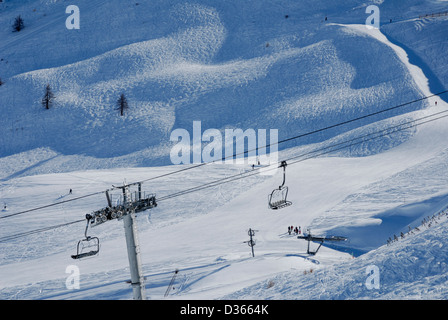 Sesselbahnen mit einer kleinen Gruppe von Skifahrern auf der Piste stehen laufen, Französisch Skigebiet Serre Chevalier in den Alpen. Stockfoto