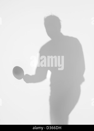 männliche Silhouette stehend halten einen Tischtennis-Schläger in der Hand, hinter eine diffuse Oberfläche Stockfoto