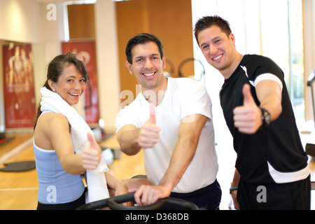 Drei Freunde in einem Fitnessstudio geben Daumen nach oben während des Trainings Stockfoto