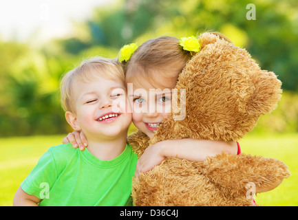 Zwei niedliche Kind umarmt im Freien, Bruder und Schwester, die Spaß am Garten im Frühjahr, nettes kleines Mädchen mit entzückenden jungen Foto Stockfoto