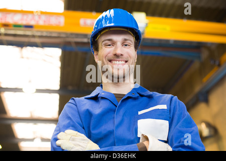 Bauarbeiter mit Helm posiert vor Kran Stockfoto