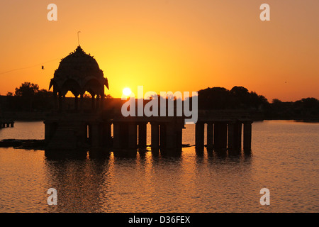 Sonnenaufgang am Gadi Sagar See mit Silhouette der Kuppel in der Mitte, Rajasthan Indien Stockfoto