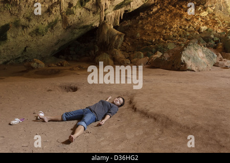 Allein Frau schläft auf Boden in tropischen Höhle, Thailand Stockfoto