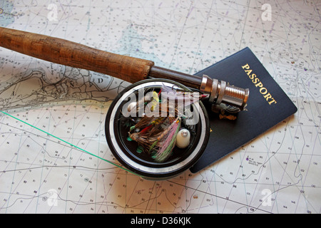 Eine Fliegenrute und Rolle beruht auf einer Seekarte mit einem Pass und künstliche fliegen. Stockfoto