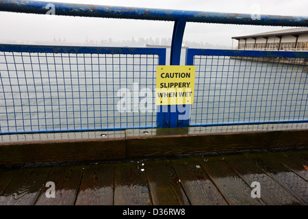 Vorsicht rutschig bei Nässe Zeichen auf hölzernen Strandpromenade Gehweg North Vancouver BC Kanada Stockfoto